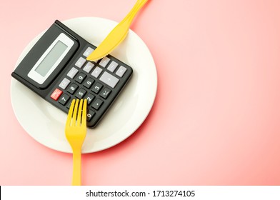 Calculate Expensive Food Spending Costs, Counting Calories And Weight Loss Program Concept With Calculator Onn Empty Plate, Yellow Fork And Knife Isolated On Pink Background With Copy Space