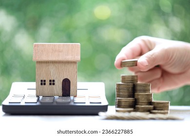 Calculating interest payments, Model house on calculator and stack of coins money on natural green background,Business investment and real estate concept - Shutterstock ID 2366227885