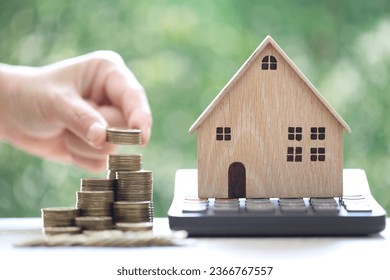 Calculating interest payments, Model house on calculator and stack of coins money on natural green background,Business investment and real estate concept - Shutterstock ID 2366767557