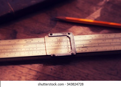 Calculation. Vintage calculating slide rule and pencil, on old desk. Intentionally shot in retro muted color. Shallow depth of field.