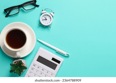 Calculator, alarm clock, pen, coffee cup, eyeglasses and plant on blue background. Business concept. Workspace. Top view. Flat lay. Copy space - Shutterstock ID 2364788909