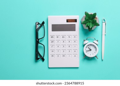 Calculator, alarm clock, pen, eyeglasses and plant on blue background. Business concept. Workspace. Top view. Flat lay - Shutterstock ID 2364788915