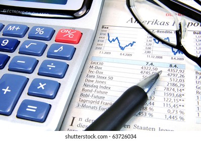 Calculator, ball-pen and glasses on top of a stock exchange report
