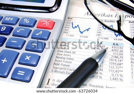 Calculator, ball-pen and glasses on top of a stock exchange report