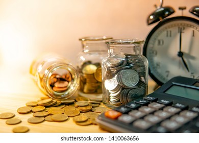 Calculator with coin in currency glass jar and clock on wooden table. Compound interest rate calculation. Financial business plan. Time investment concept
