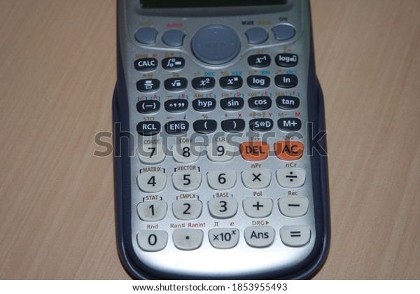 Calculator with colored keys or buttons\
isolated on a wooden\
background
