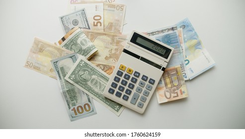 Calculator And Falling Paper Currency. View Of An Old Calculator And International Paper Currency. Counted Summ On Calculators Screen. Money Signs. Counting Money. Home Finances Concept.