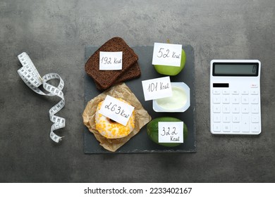 Calculator and food products with calorific value tags on dark grey table, flat lay. Weight loss concept - Shutterstock ID 2233402167