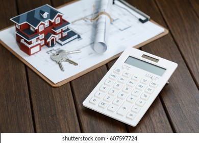 a calculator in front of a Villa house model with a blueprint