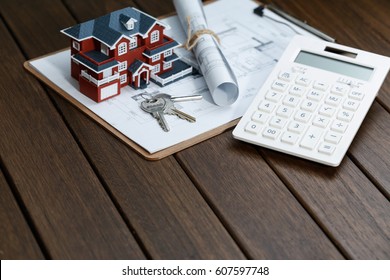 a calculator in front of a Villa house model with a blueprint
