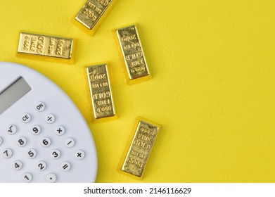 Calculator And Gold Bars Isolated On A Yellow Background