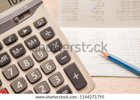 The calculator has a backdrop as a bank book and pencil, placed on a wooden desk.
