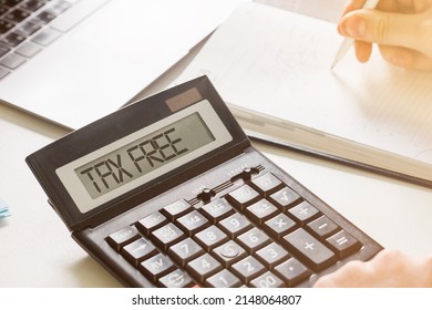 Calculator with inscription "TAX FREE". Hand calculating the tax-free percentage for services or products.