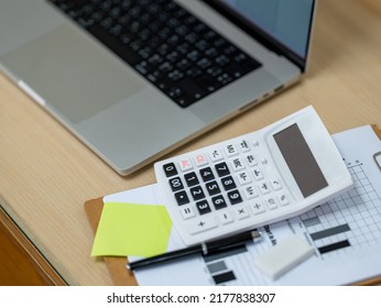 calculator with laptop computer and document report placed on wood desk in office.Business finances and accounting concept