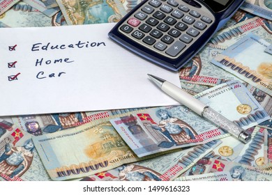 Calculator and a list to do with marked education, home and car on Armenian Dram in AMD 100,000 banknotes. Business and finance concept