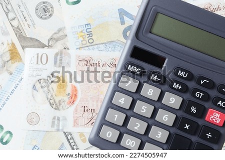 Calculator on money bills. Different currency banquetes background. Various currency texture. USA american dollar. Twenty euro blue bill. Great Britain Pound cash background. Pile of cash pattern. 