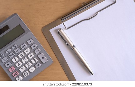 Calculator , pen and clipboard with blank paper on the desk . - Powered by Shutterstock