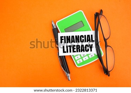 calculator, pen and glasses with the word financial literacy. financial concept