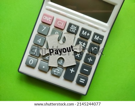 Calculator and puzzle pieces with the concept of the word Payout.