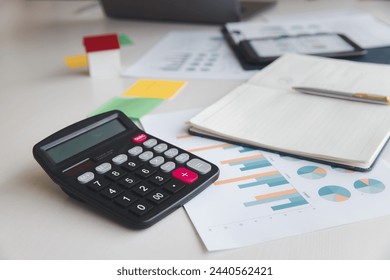Calculator, report paper, notebook, pen and office supplies on office desk. Business chart showing financial success at the stock market.