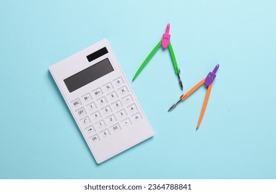 Calculator and Stationery Compasses on blue background. Top view - Shutterstock ID 2364788841
