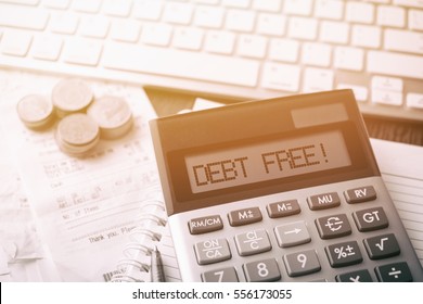 Calculator with text Debt Free!. Calculator, currency, book, bills and computer keyboard on wooden table. Business, finance conceptual. 