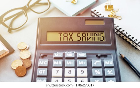Calculator with text Tax Saving. Calculator, glasses, book, money and pen on table. Business, finance conceptual.