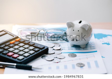 Calculator with text Tax Saving. Calculator, Piggy Bank, coins, business graph and pen on wooden table.
Concept saving money for finance accounting