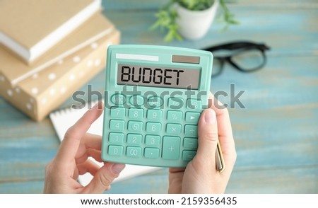 Calculator with the word BUDGET on the display. Pen, eyeglasses and notepad on the diagrams. Concept photo