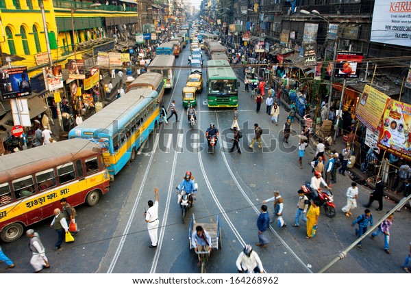 CALCUTTA, INDIA - JAN 18: Pedestrians cross the\
road in front of motorcycles, cars and buses at the crossroads on\
January 18, 2013 in India. Kolkata has a density of 814.80 vehicles\
per km road length