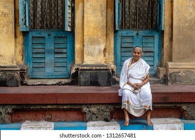 Calcutta (Kolkata), India-January 21, 2019: Traditionally dressed old woman sitting in front of her colorful house in the narrow streets of Calcutta.
