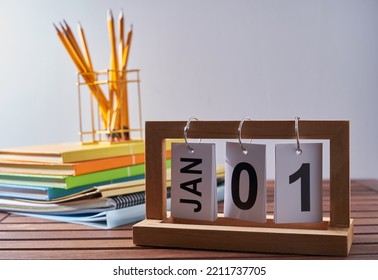 Calendar 1st january with stack of book and penin pencil holder against white wall - Shutterstock ID 2211737705