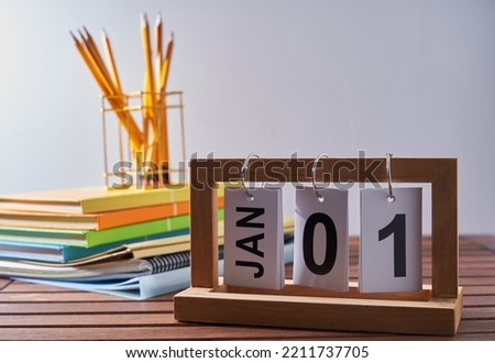 Calendar 1st january with stack of book and penin pencil holder against white wall