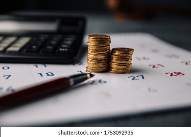 Calendar, calculator and stack of coins in a office