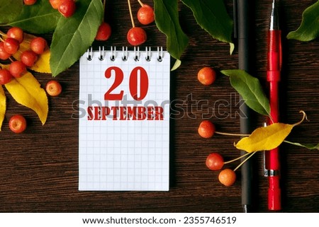 calendar date on wooden dark desktop background with autumn leaves and small apples. September 20 is the twentieth day of the month.