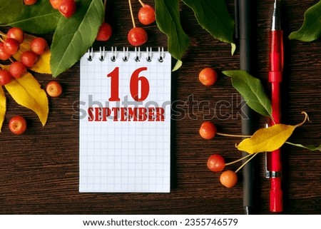 calendar date on wooden dark desktop background with autumn leaves and small apples. September 16 is the sixteenth day of the month.