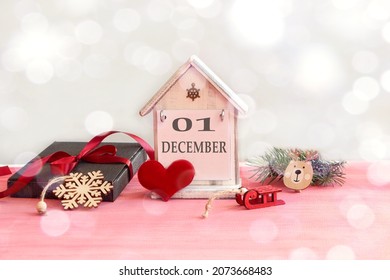 Calendar for December 1: decorative house with the name of the month in English, number 01, gift wrapped, tied with a red ribbon, red heart, New Year's toys, bokeh. - Shutterstock ID 2073668483