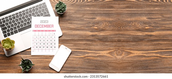 Calendar for December 2023, modern laptop and mobile phone on wooden background with space for text - Shutterstock ID 2313572661