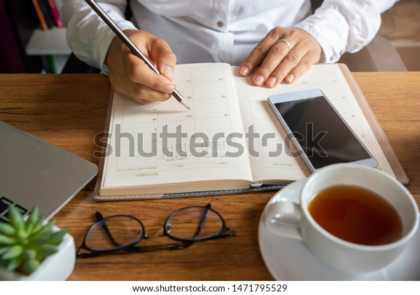 Calendar and diary,\
Planner writing daily appointment. Woman plan and noted schedule\
book (holiday trip) on book at home office. Calendar reminder event\
for planner concept