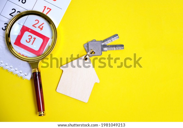 Calendar for end of month Magnifier Keys to house or\
apartment on a yellow background Concept Buying an Apartment House\
New Year Gift