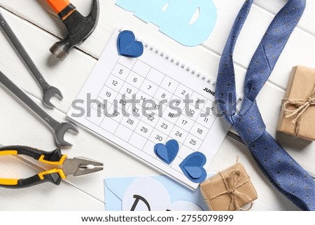 Calendar with gift boxes, instruments, tie and word DAD on white wooden background. Father's day celebration