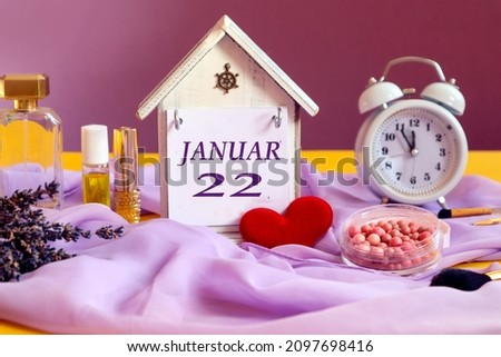 Calendar for January 22: decorative house with the name of the month in English, number 22, alarm clock, lavender bouquet, powder, body care products, light pastel scarf, red heart