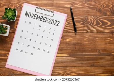 Calendar page of November 2022 and flowerpots on dark wooden background. Black Friday