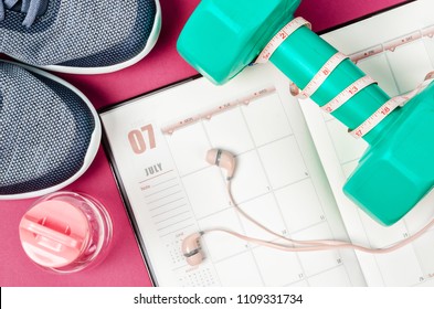 Calendar Plan With Green Dumbbell And Sneakers On Pink Background. Workout Plan Concept.