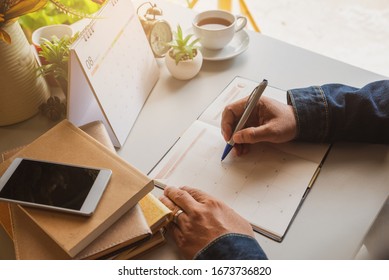 Calendar Reminder Event Concept. Man Hand Planner Or Organizer Writing On Diary And Calendar Page. Student Holding Smartphone And Planning Appointment. Male Noted And Count Down Schedule Day On Book