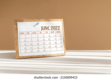 Calendar sheet for 2022. Desktop calendar for month of June, attached to cork board with a button on desktop. Concept of event planning, reminders.