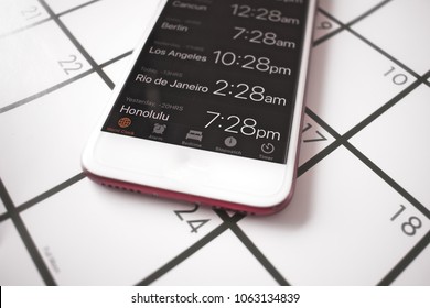 A calendar and world time clock on a mobile phone are used to plan traveling to different time zones