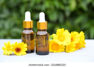 Calendula Beauty Products. Natural Calendula Oil In Dropper Bottles Against Green Leaves As Natural Background. Herbal Cosmetic Oil For Skincare. Selective Focus