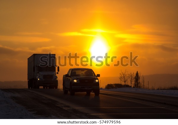Calgary, AB - December 8, 2016. Traffic on the\
road silhouetted by a winter\
sunset