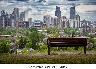 Calgary Alberta Canada, July 02 2022: A Park Bench With No People Overlooking The Downtown Skyline And Inner City Homes.